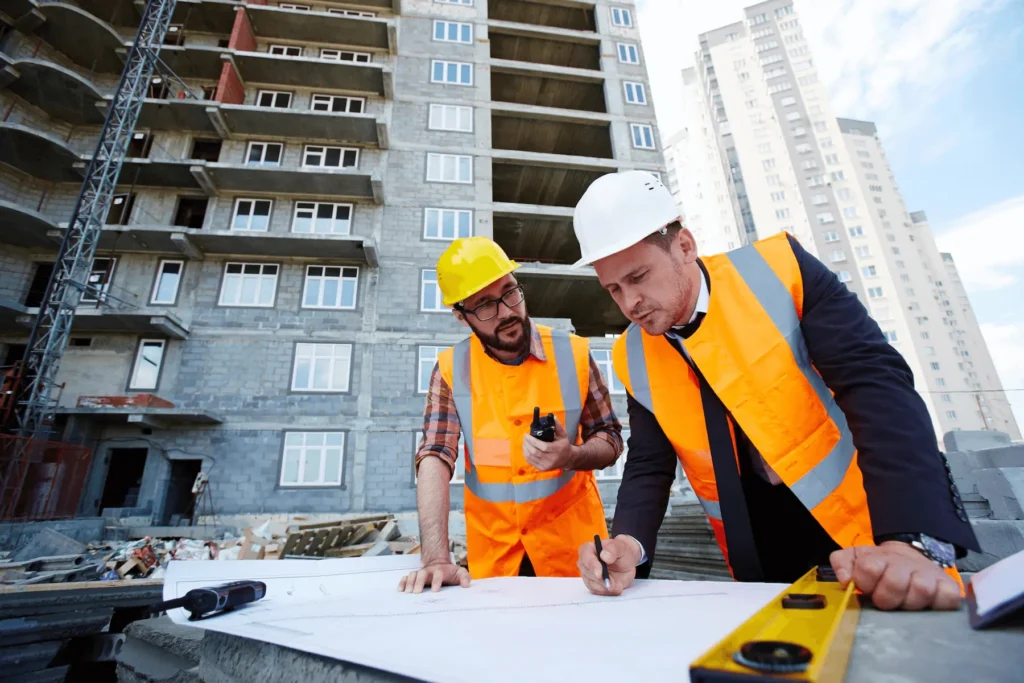 Zwei Fachkräfte besprechen einen Bauplan auf der Baustelle
